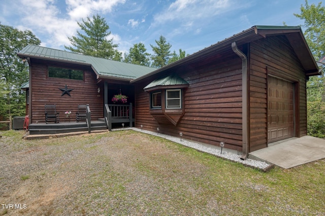 rustic home with a front yard, a garage, metal roof, and central AC