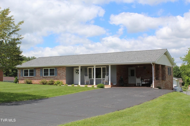 ranch-style home featuring driveway, brick siding, a front lawn, and covered porch
