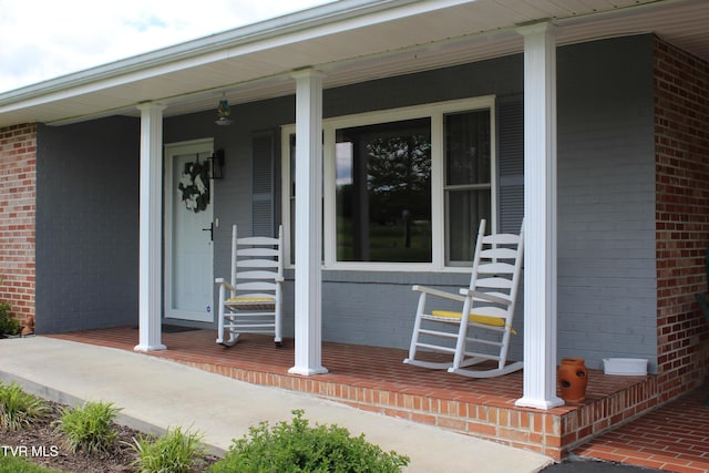 property entrance featuring covered porch and brick siding