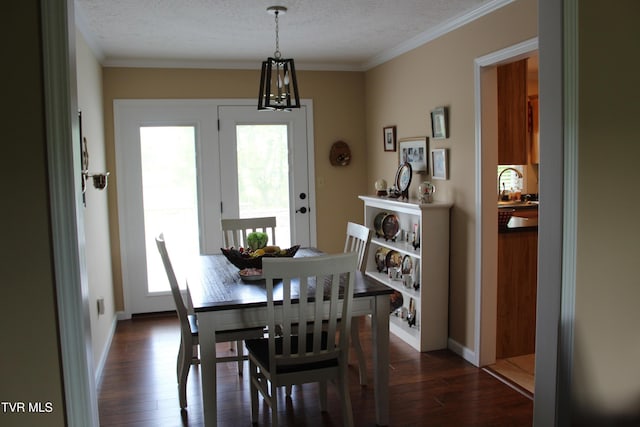 dining area featuring dark wood-type flooring, a chandelier, ornamental molding, and a textured ceiling