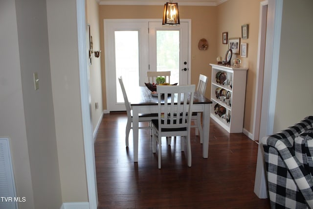 dining space featuring crown molding, dark wood-style flooring, and baseboards