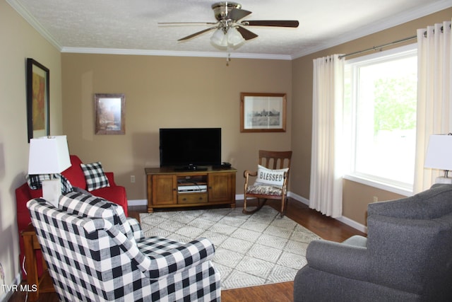 living area featuring wood finished floors, plenty of natural light, a ceiling fan, crown molding, and baseboards