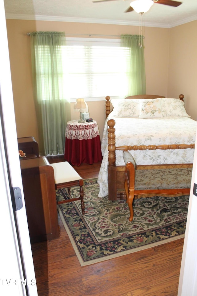 bedroom with wood finished floors, ornamental molding, and ceiling fan