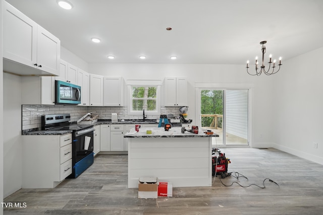 173 Paynetown Rd, Telford, TN 37690 - kitchen with stainless steel microwave, tasteful backsplash, range with electric stovetop, a chandelier, and light wood-style flooring
