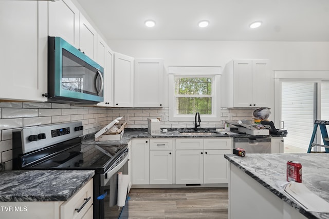 173 Paynetown Rd, Telford, TN 37690 - kitchen with a sink, dark stone counters, tasteful backsplash, light wood-type flooring, and electric range
