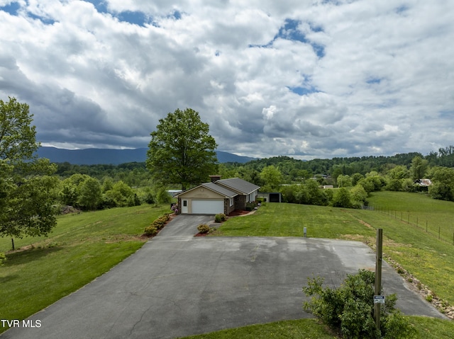 view of front facade with asphalt driveway, an attached garage, a mountain view, and a chimney