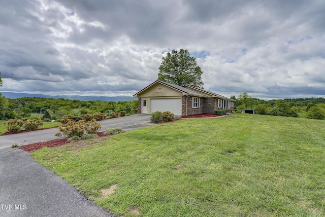 ranch-style home featuring asphalt driveway, an attached garage, a front lawn, and brick siding