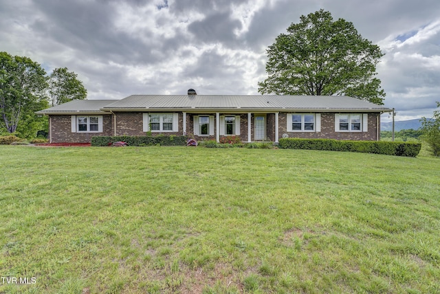 single story home featuring brick siding, a front lawn, and metal roof