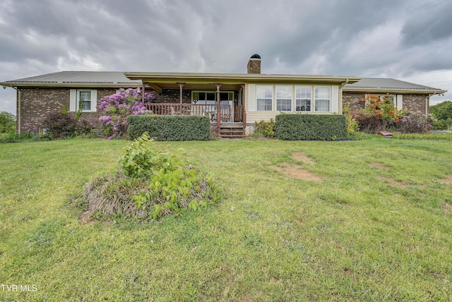 ranch-style house featuring a chimney, a front lawn, brick siding, covered porch, and metal roof