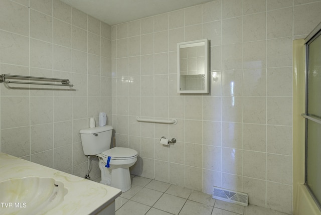 bathroom featuring tile patterned floors, tile walls, a shower with shower door, toilet, and vanity