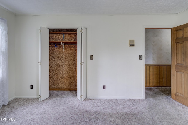 unfurnished bedroom featuring carpet floors, ornamental molding, a wainscoted wall, and baseboards