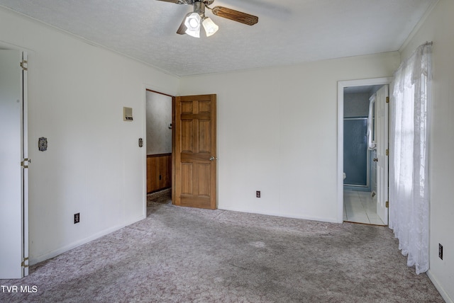 unfurnished bedroom with carpet, crown molding, baseboards, ensuite bath, and a ceiling fan