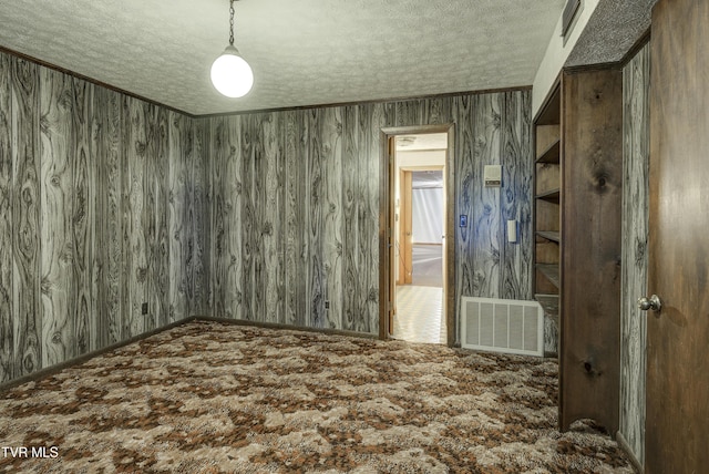 carpeted empty room with a textured ceiling and crown molding