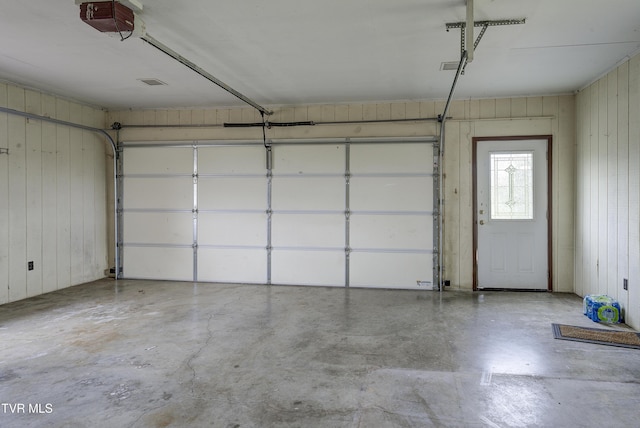 garage featuring a garage door opener and wooden walls