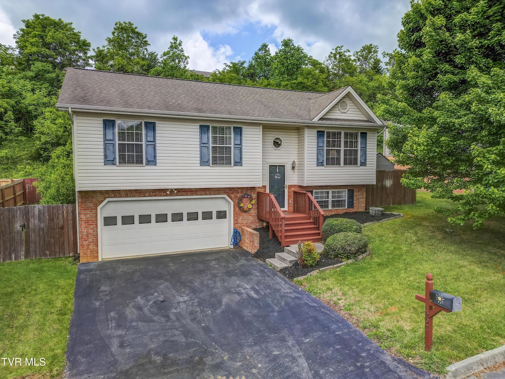 split foyer home featuring asphalt driveway, a garage, brick siding, and roof with shingles