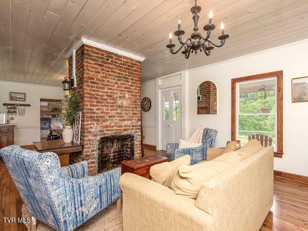 26354 Pewter Ln, Abingdon, VA 24211 - living area with a chandelier, wooden ceiling, wood finished floors, a brick fireplace, and baseboards