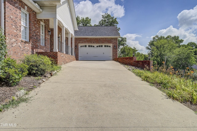 view of side of home featuring concrete driveway, brick siding, an attached garage, and roof with shingles