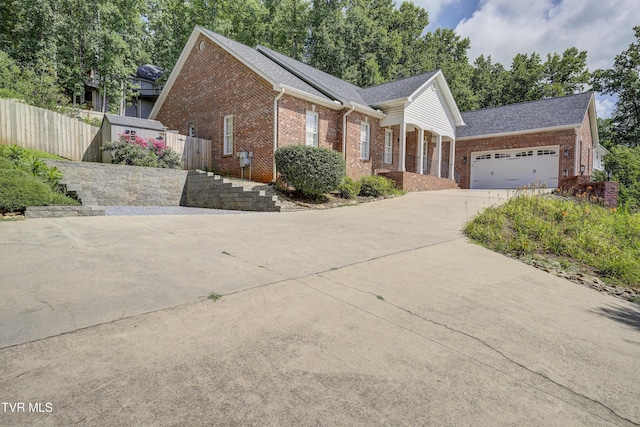 view of front facade with concrete driveway, roof mounted solar panels, an attached garage, brick siding, and a shingled roof