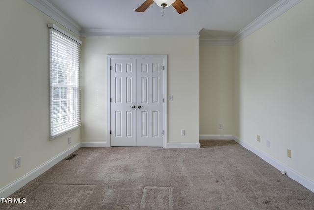 unfurnished bedroom with ornamental molding, carpet flooring, a closet, and ceiling fan
