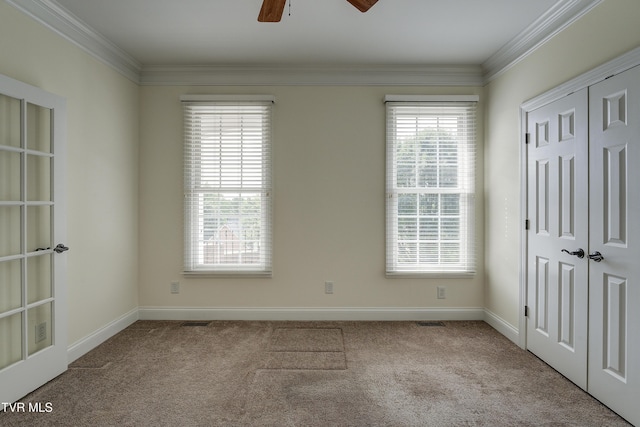 unfurnished bedroom with carpet, crown molding, ceiling fan, and a closet