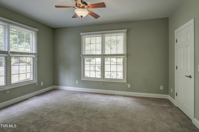 carpeted spare room with plenty of natural light and ceiling fan