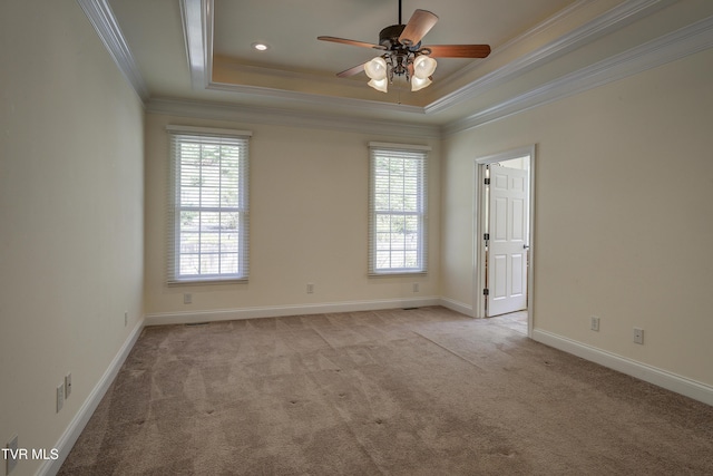 unfurnished room with light colored carpet, crown molding, a ceiling fan, and a raised ceiling