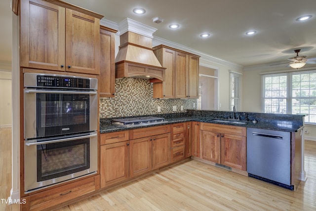 kitchen with appliances with stainless steel finishes, ornamental molding, light wood-style flooring, a peninsula, and backsplash