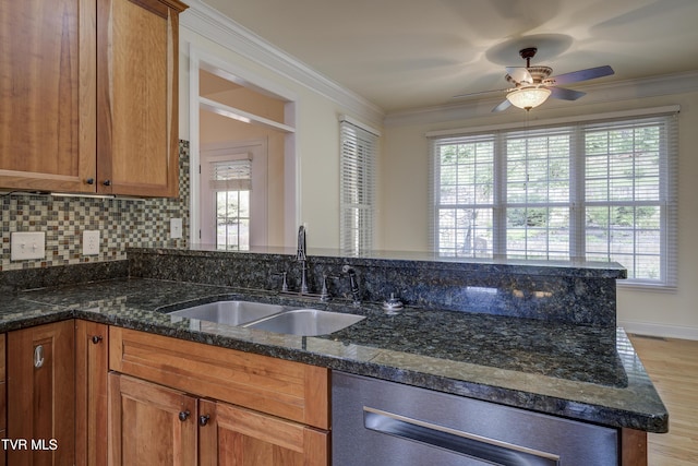 kitchen with a ceiling fan, dark stone countertops, brown cabinetry, crown molding, and dishwasher