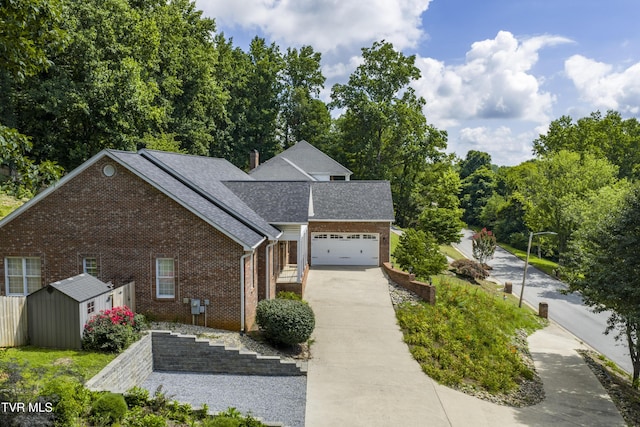 view of front of home featuring concrete driveway, brick siding, a garage, and an outdoor structure