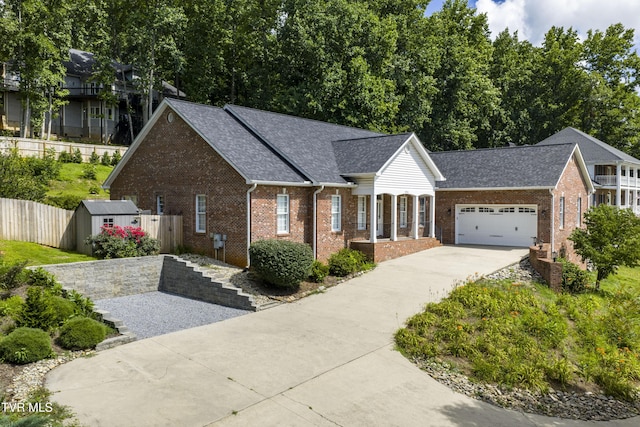 view of front of property featuring brick siding, roof with shingles, concrete driveway, an attached garage, and an outbuilding