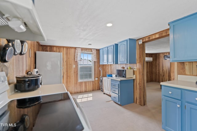 590 Kingsport Hwy, Greeneville, TN 37745 - kitchen with blue cabinetry, wood walls, under cabinet range hood, freestanding refrigerator, and black microwave