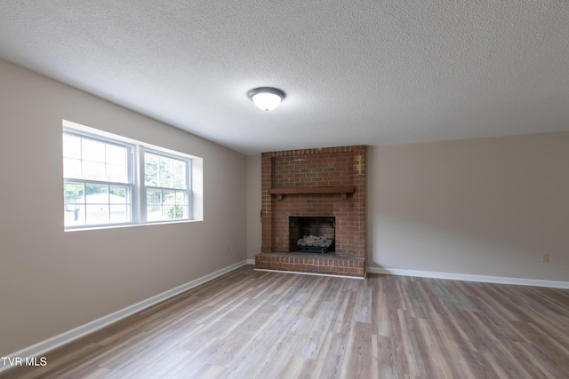7324 White Pine Cir, Bristol, VA 24202 - unfurnished living room with wood finished floors, a textured ceiling, a fireplace, and baseboards