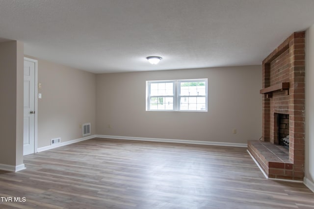7324 White Pine Cir, Bristol, VA 24202 - unfurnished living room featuring a brick fireplace, wood finished floors, baseboards, and a textured ceiling