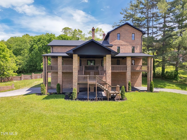 view of front of property featuring a front yard, brick siding, stairway, and a porch