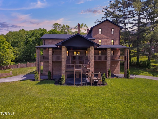 view of front of property featuring a front lawn, brick siding, stairs, and a porch