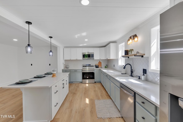 kitchen with appliances with stainless steel finishes, a sink, backsplash, light wood-style floors, and recessed lighting