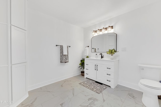 bathroom featuring baseboards, marble look tile flooring, toilet, and vanity