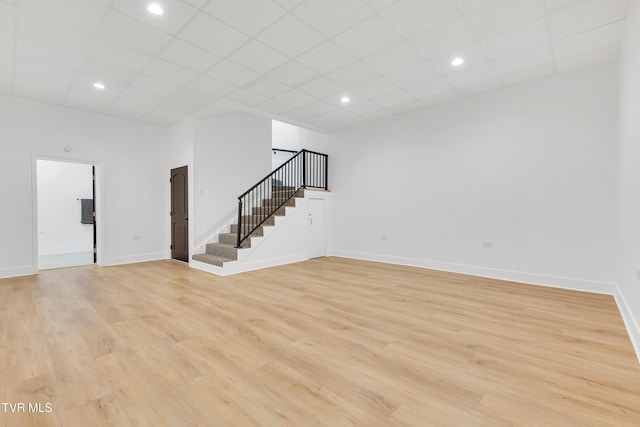 basement with stairs, light wood-style floors, a paneled ceiling, baseboards, and recessed lighting