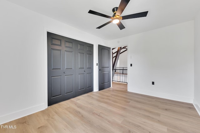 unfurnished bedroom featuring light wood-style flooring, baseboards, and a closet