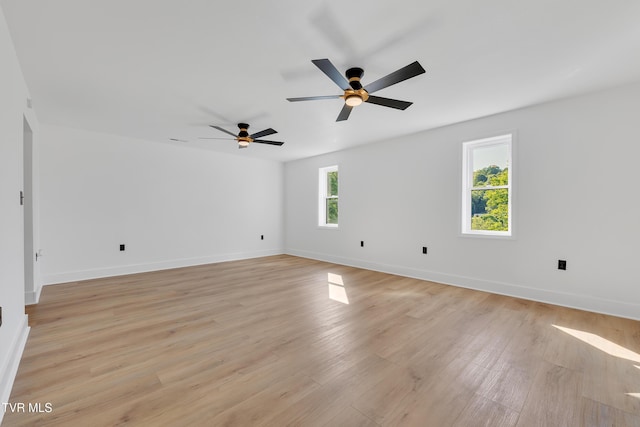 spare room featuring a ceiling fan, light wood finished floors, and baseboards