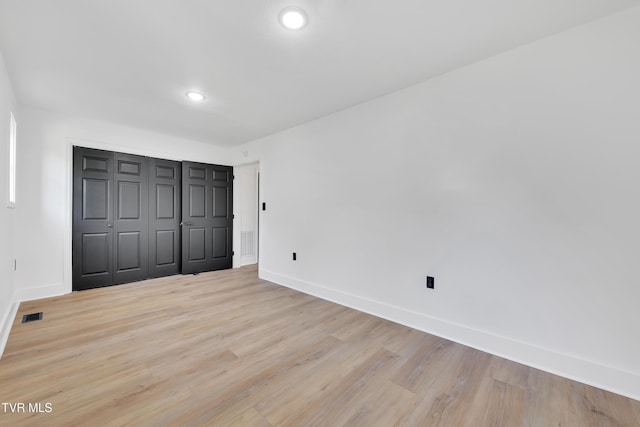 unfurnished bedroom featuring baseboards, light wood finished floors, recessed lighting, and a closet