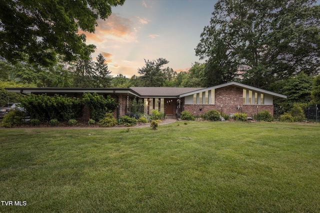 mid-century inspired home featuring brick siding and a yard