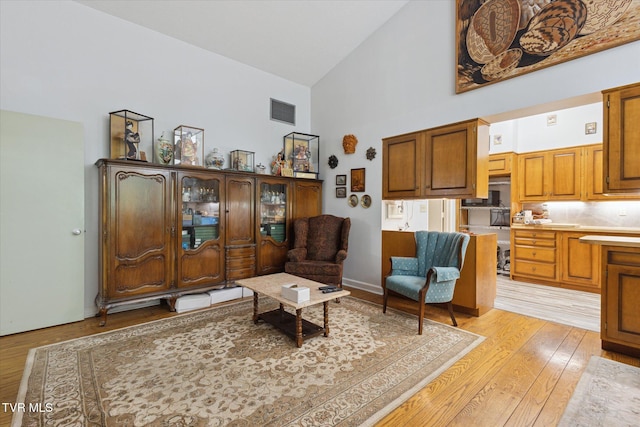 sitting room with high vaulted ceiling and light wood-style floors