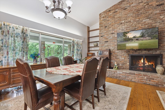 dining room with a fireplace, a chandelier, wood-type flooring, and high vaulted ceiling