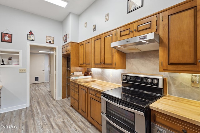 kitchen featuring range with two ovens, butcher block counters, under cabinet range hood, backsplash, and brown cabinets