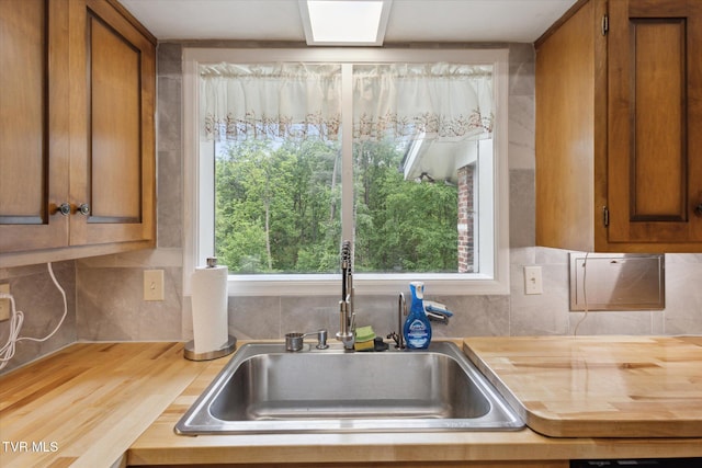 kitchen with butcher block counters, a sink, brown cabinetry, and decorative backsplash