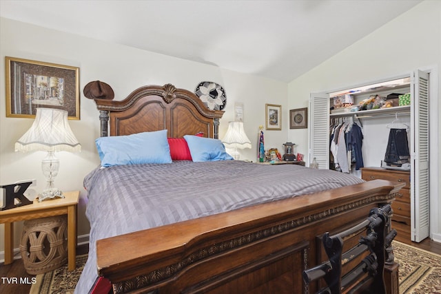 bedroom with vaulted ceiling, wood finished floors, and a closet
