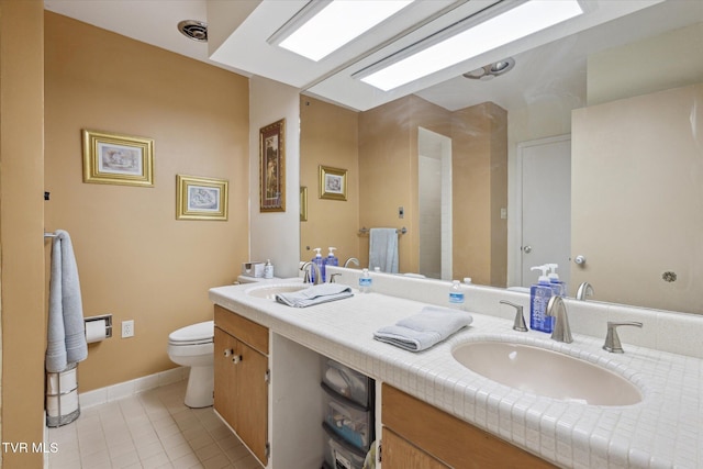 bathroom featuring tile patterned flooring, toilet, double vanity, and baseboards