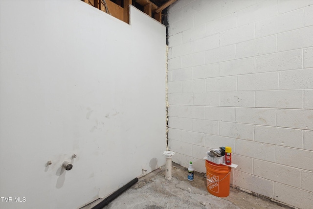 clothes washing area with concrete block wall