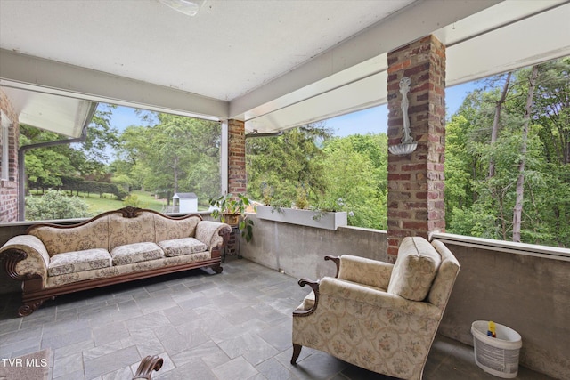 sunroom / solarium with stone tile flooring and view of scattered trees